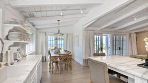 Una cocina amplia con armarios blancos, una mesa de comedor de madera y una isla de mármol.