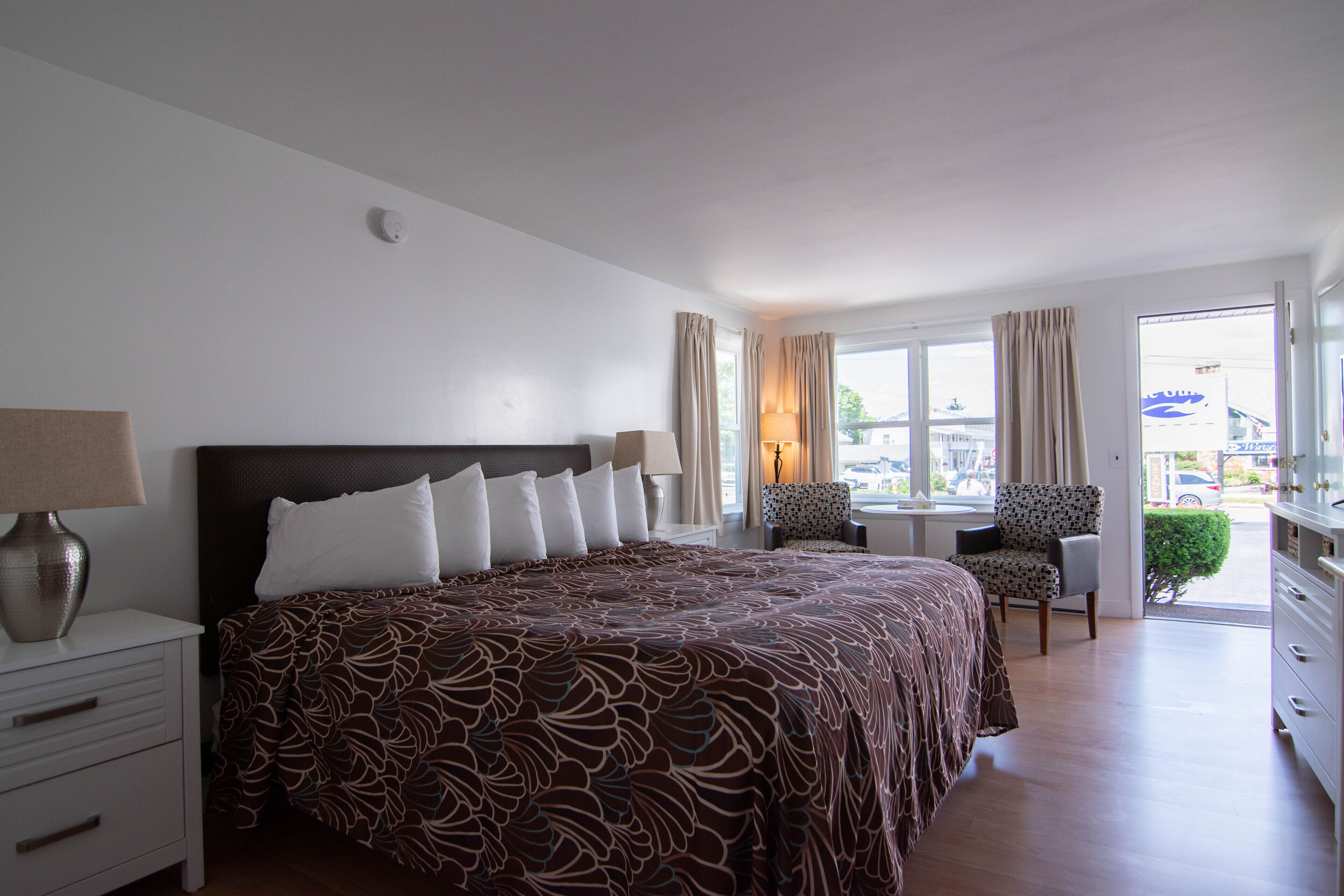 Ein Hotelzimmer mit einem großen Bett, einem Schreibtisch, zwei Stühlen und Blick ins Freie.