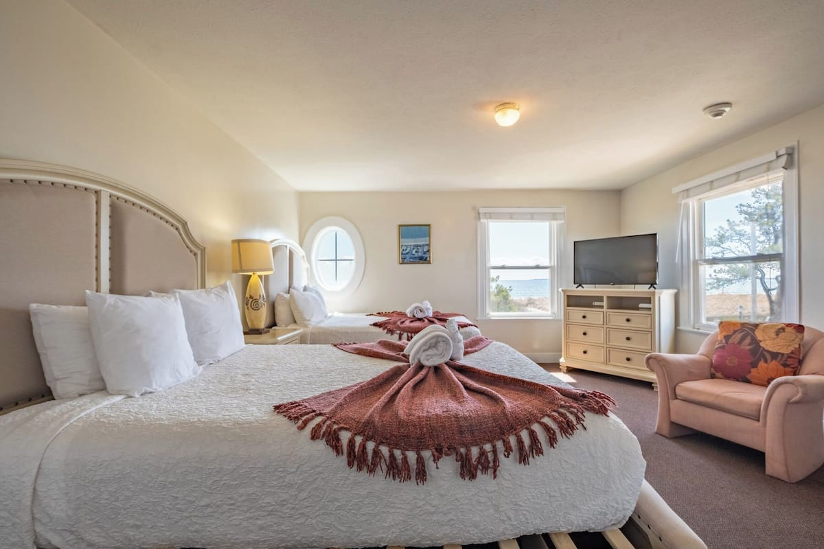 A hotel room with a bed, a TV, a dresser, and a chair.