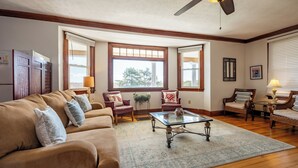 A spacious living room with a large window, a ceiling fan, and a wooden floor. - The Gull Oceanside Inn & Motel  (Old Orchard Beach)