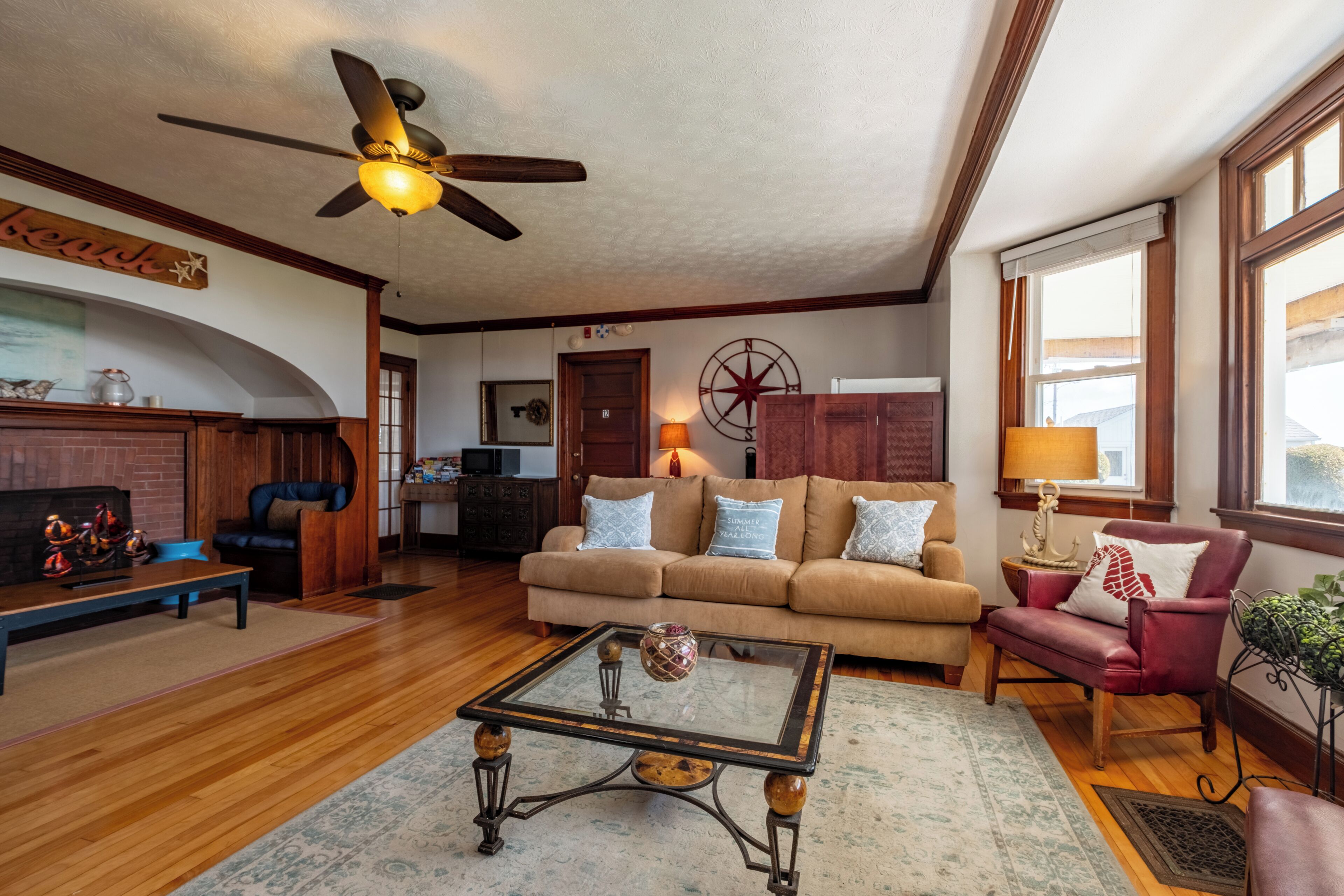 A living room with a ceiling fan, a sofa, a coffee table, and a fireplace.