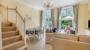 A spacious living room with a staircase, a dining area, and a view of the garden through large windows. - 3 bedroom accommodation in Cromer (Cromer)