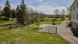 Ein Wohngebiet mit einem gepflasterten Weg, einem eingezäunten Spielplatz und einem Gebäude mit mehreren Fenstern.