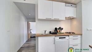Une cuisine de taille réduite avec des meubles blancs, un lave-vaisselle et un plan de travail en bois.