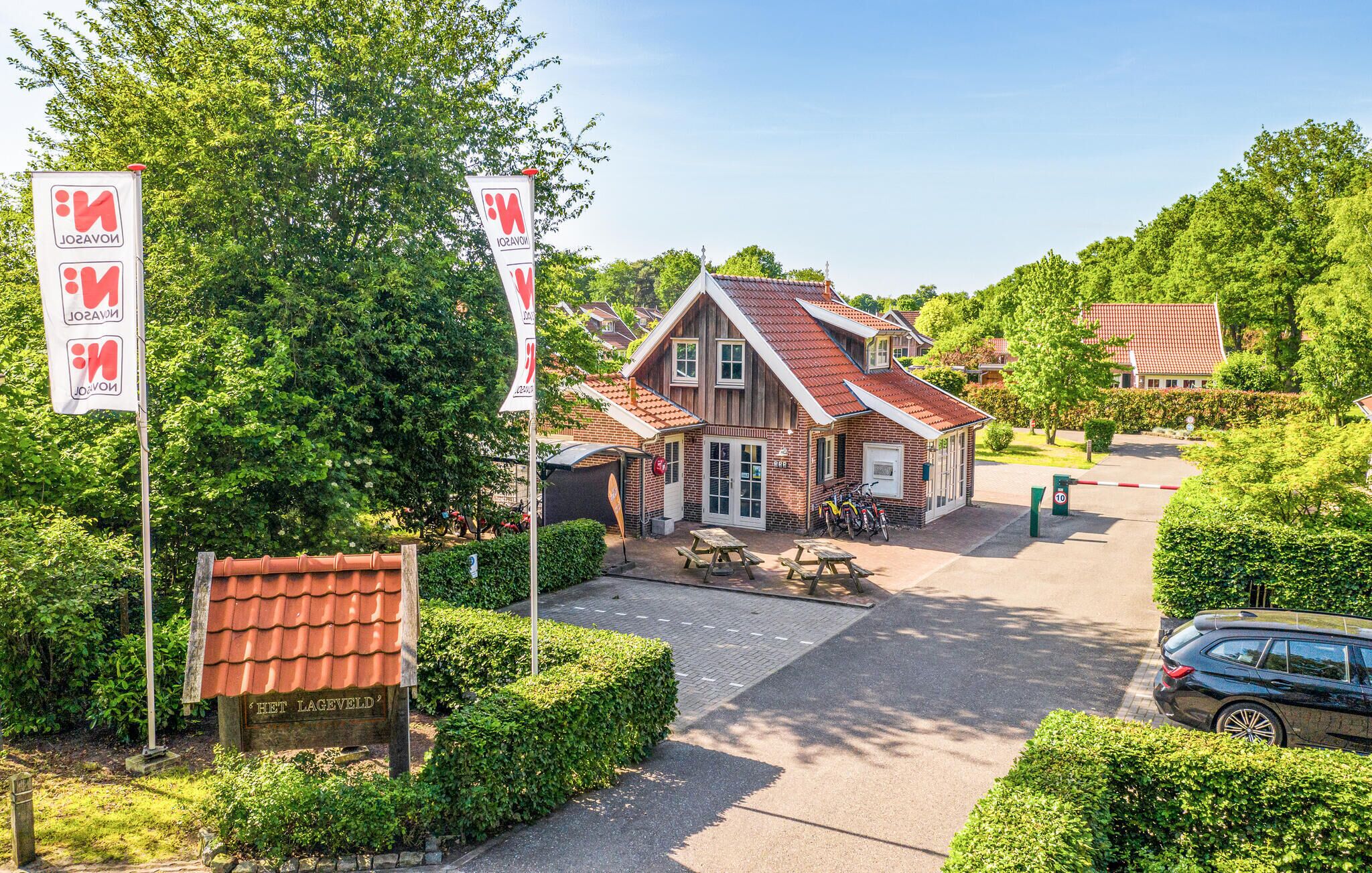 Une maison traditionnelle en bois, avec un toit recouvert de tuiles rouges, un petit garage attenant et une allée pavée.