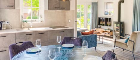Una cocina moderna con zona de comedor, ventanas amplias y televisor integrado.