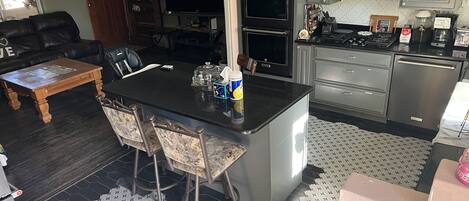 A kitchen with a central island, built-in appliances, and a dining area with a coffee table and chairs.
