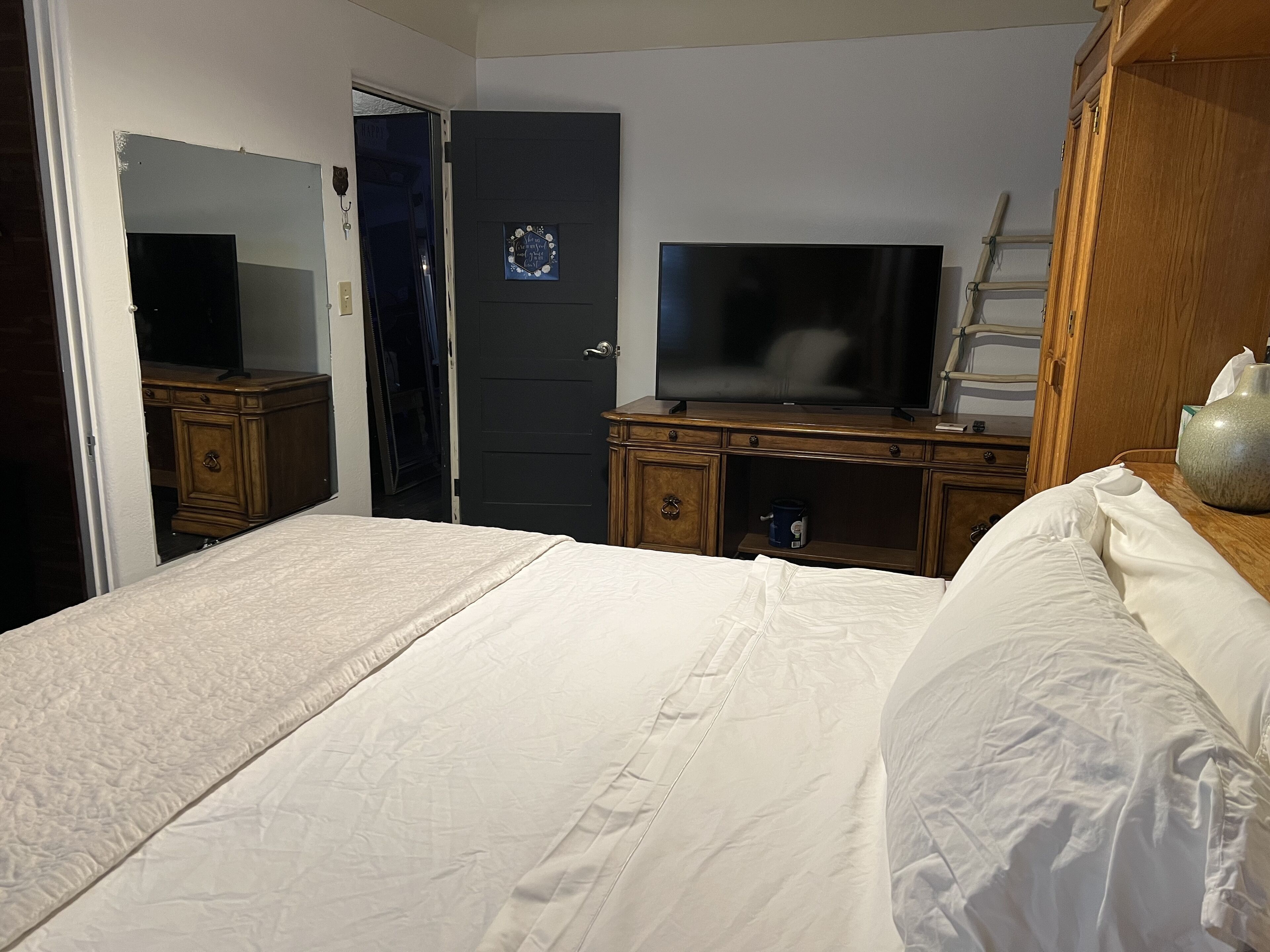 Una habitación de hotel con una cama, televisor, cómoda de madera y una puerta.