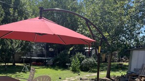An outdoor patio with a red umbrella, white plastic chairs, and a concrete table. - Old Town 2BD1BA, Pet friendly (Albuquerque)