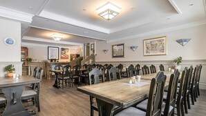 Un comedor con varias mesas y sillas, una escalera y cuadros en las paredes.