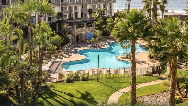 A resort with a large pool, palm trees, and a view of the ocean. - Sunset Harbor and Ocean Views, Modern Coastal Design, Beachfront Resort (Oceanside)