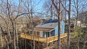 Una casa con terraza de madera y techo metálico, rodeada de árboles.