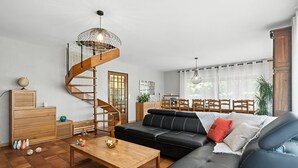 Ein modernes Wohnzimmer mit einer schwarzen Ledersofa, einem Holztisch und einer Wendeltreppe.