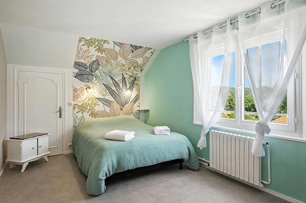 Une chambre à coucher avec un lit, une table de chevet, un radiateur et une fenêtre avec des rideaux.