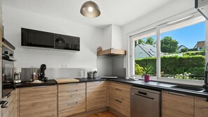 Eine moderne Küche mit Holdekor, einer schwarzen Arbeitsplatte und einem Fenster mit Blick auf eine grüne Landschaft.