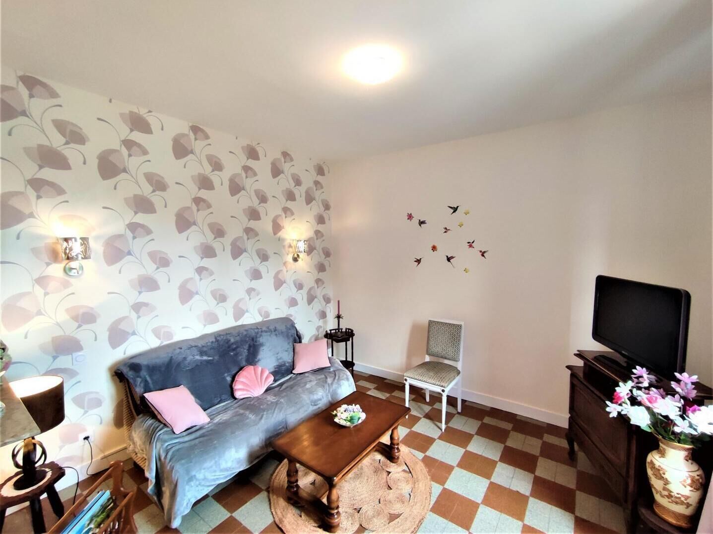 Una sala de estar acogedora con sofá, sillón, una mesita de centro, televisor y adhesivos decorativos en la pared.
