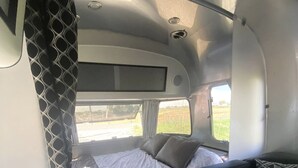 En kompakt autocamper-indretning med seng, sofa og lille bord.