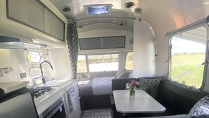 En kompakt autocamper indretning med et tekøkken, spiseplads og soveplads.