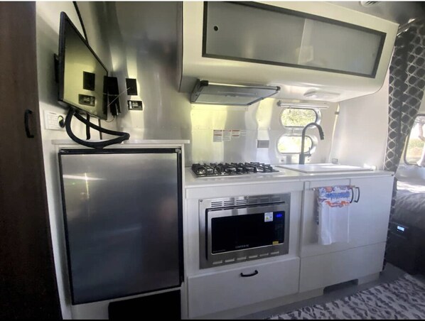 A compact kitchenette with a refrigerator, microwave, stove, and sink.