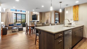 A modern kitchen with a large island, built-in appliances, and a dining area with a view. - Grand Colorado on Peak 8 1 Bedroom - Ski in/out (Breckenridge)