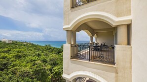 A multi-story building with balconies overlooking a lush green landscape and a view of the ocean. - Luxury Condo Steps from Ocean with Great Views at The Landmark Resort of Cozumel (San Miguel de Cozumel)