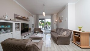 Uma sala de estar moderna com sofá, poltrona, televisão e uma estante de madeira.