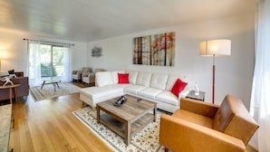 A modern living room with a white sectional sofa, a wooden coffee table, and a brown leather armchair. - 3 Mi to Downtown: Pittsburgh Home w/ Balcony! (Pittsburgh)