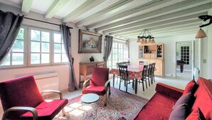 Ein gemütliches Wohnzimmer mit einem roten Sofa, einem Essbereich mit Tisch und Stühlen sowie einer Küchenzeile mit Schränken und einer Hängeleuchte.