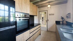 Eine moderne Küche mit Holzschränken, einem schwarzen Kühlschrank und einem eingebauten Backofen.