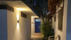 A narrow, well-lit corridor with a bench and a door at the end. - San José HOUSE (Leticia)