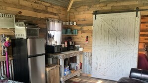 Uma cabana rústica com cozinha compacta, uma cama e um sofá de couro.