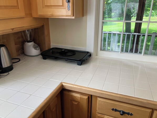 A kitchen with a countertop, a blender, a toaster, and a window with a view of greenery. - Windham Hill Inn (West Townshend)