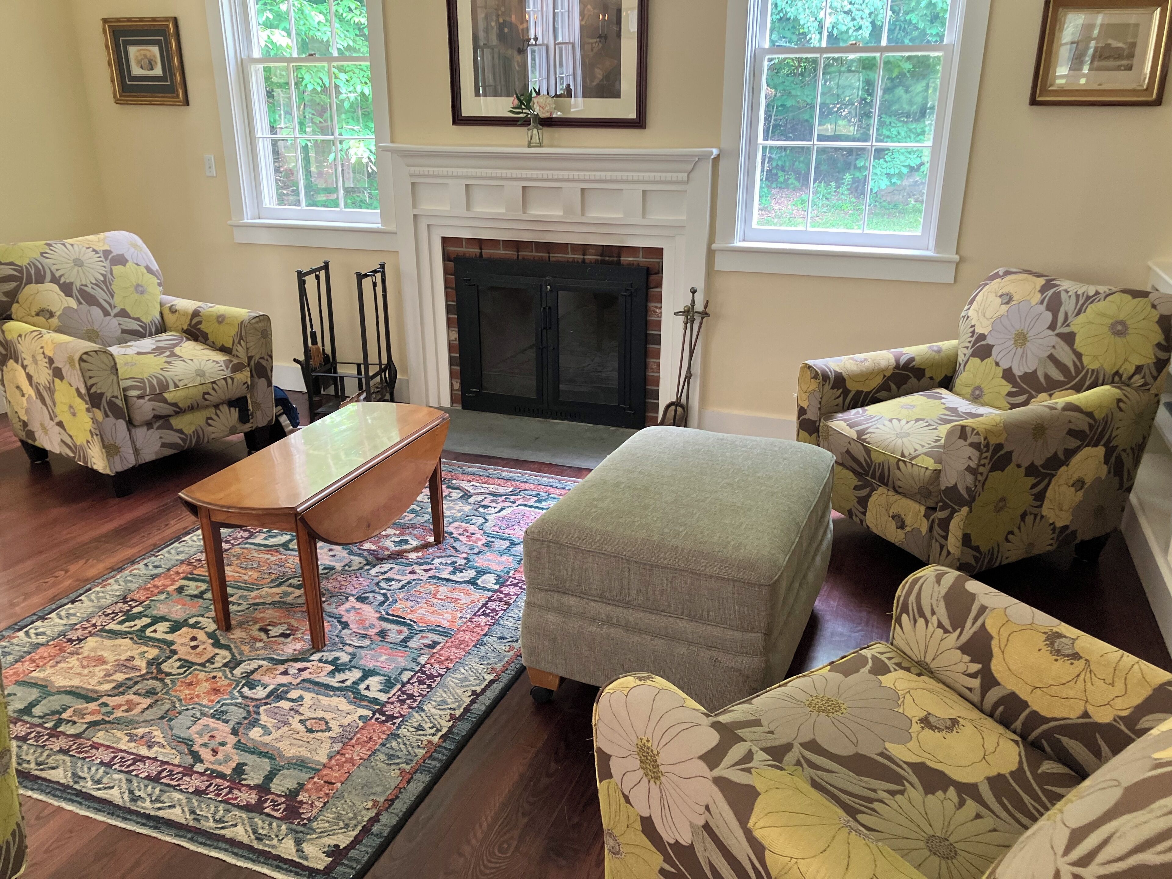 A living room with floral armchairs, a wooden coffee table, a patterned rug, and a fireplace.
