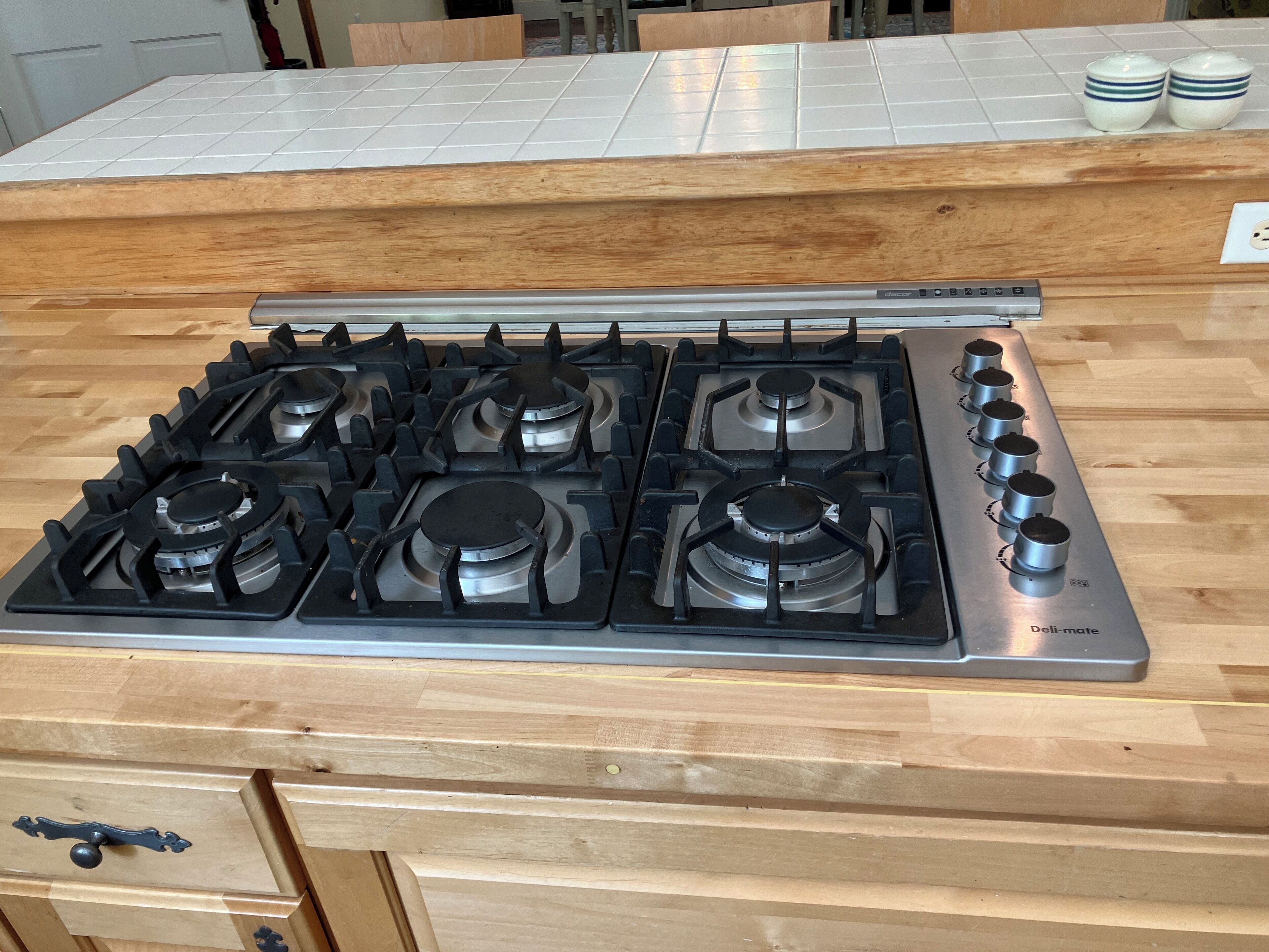 A kitchen with a gas stove, wooden countertop, and a drawer with a handle.