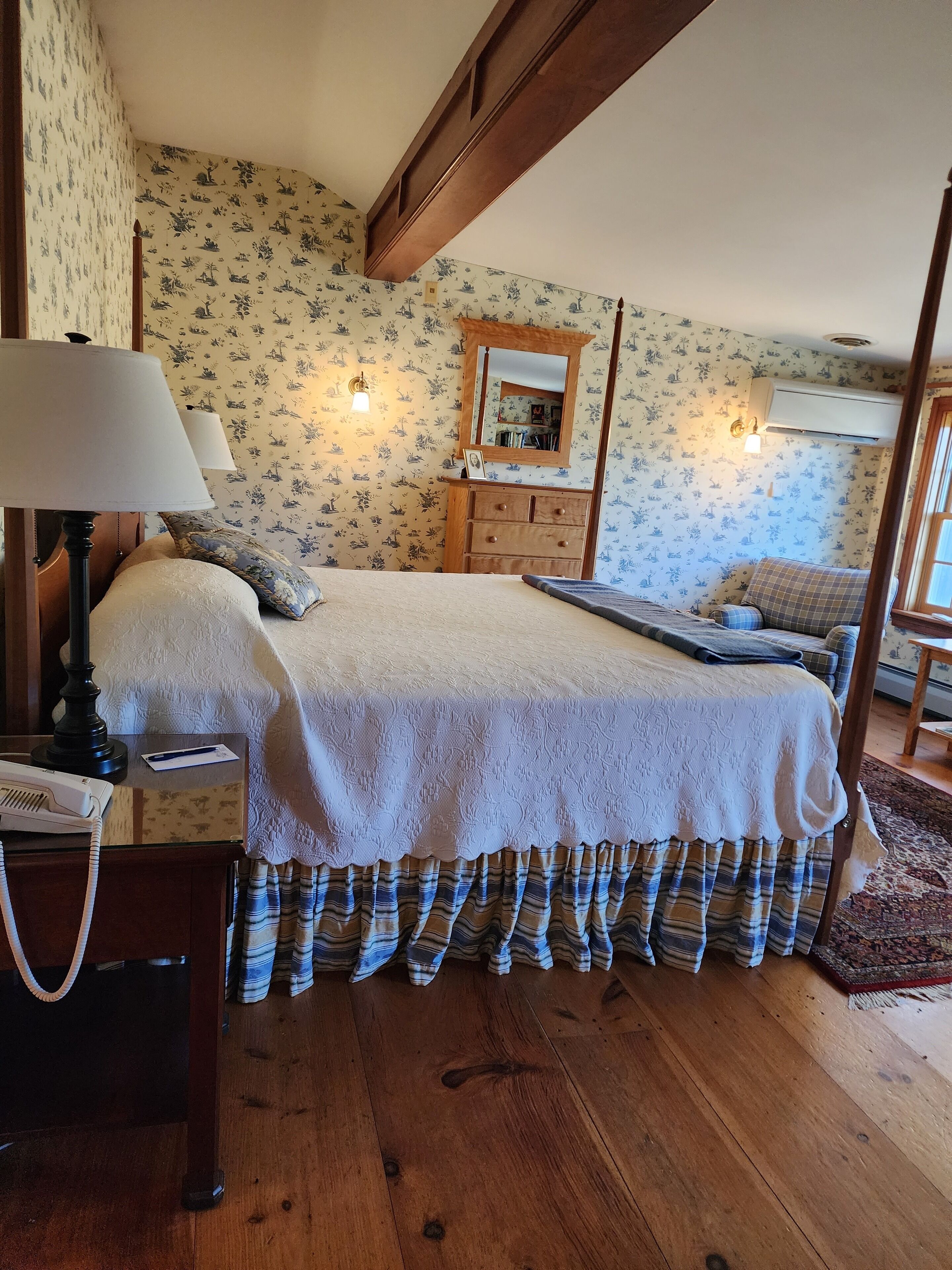 A bedroom with a bed, a dresser, a lamp, and a mirror.