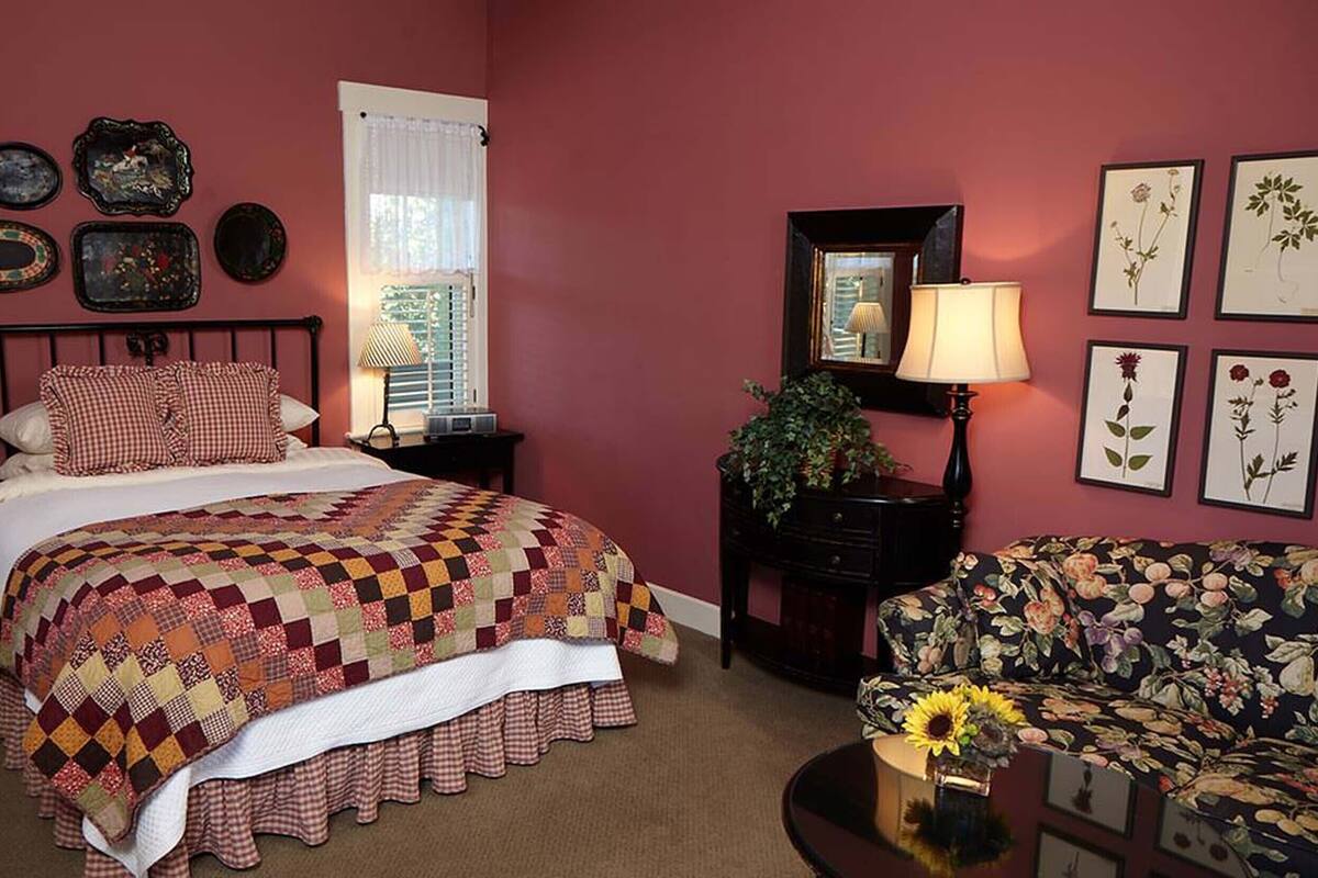 A bedroom with a bed, a nightstand, a dresser, a chair, and a window with curtains.