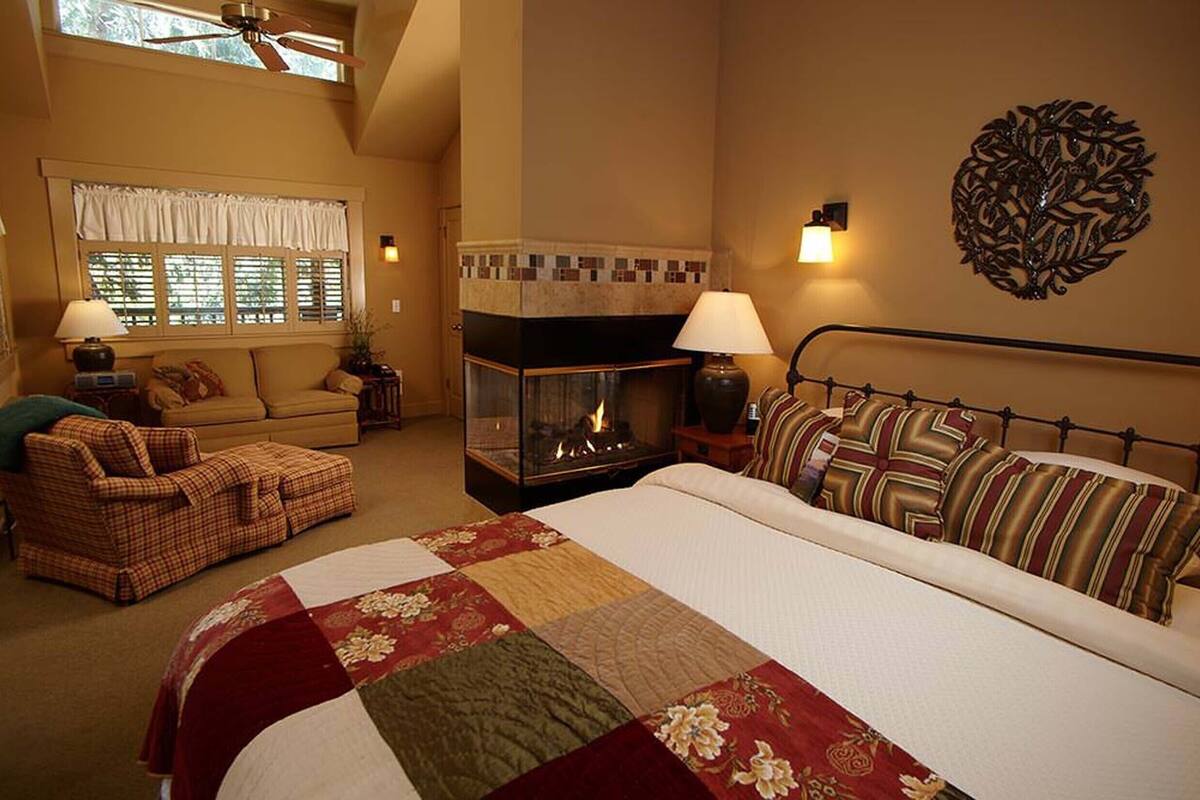 A bedroom with a large bed, a fireplace, a sofa, and a decorative wall piece.
