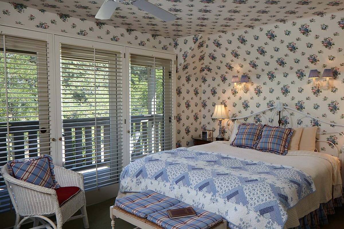 A bedroom with a bed, two nightstands, a chair, and a bench.