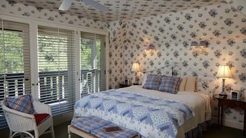 Un dormitorio con cama, dos mesitas de noche, una silla y un banco.