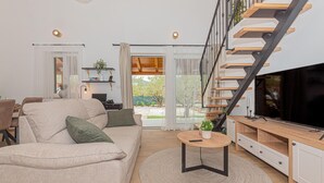 A modern living room with a sofa, a coffee table, a TV, and a staircase.