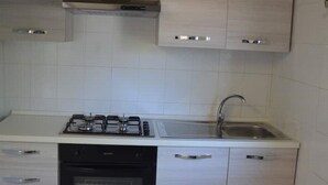A kitchen with white cabinets, a stove, a sink, and a dishwasher.