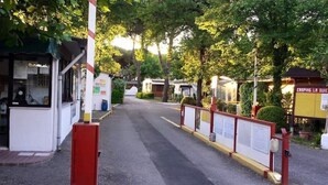 A gated entrance to a campground with a clear path leading to a building with a sign that reads "CAMPING LA QUIE".