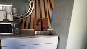 Een kitchenette met een ingebouwde magnetron, koffiezetapparaat en spoelbak.