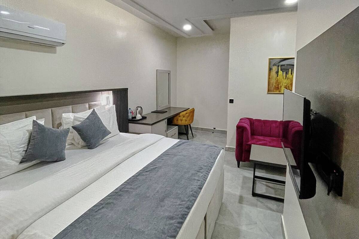 Una habitación de hotel moderna con una cama grande, un escritorio, una silla y un televisor.