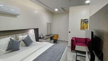 Une chambre d’hôtel moderne équipée d’un grand lit, d’un bureau, d’une chaise et d’un téléviseur.