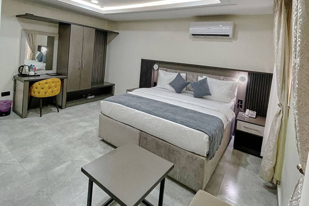 Una habitación de hotel moderna con una cama grande, un escritorio, una silla y una mesita.
