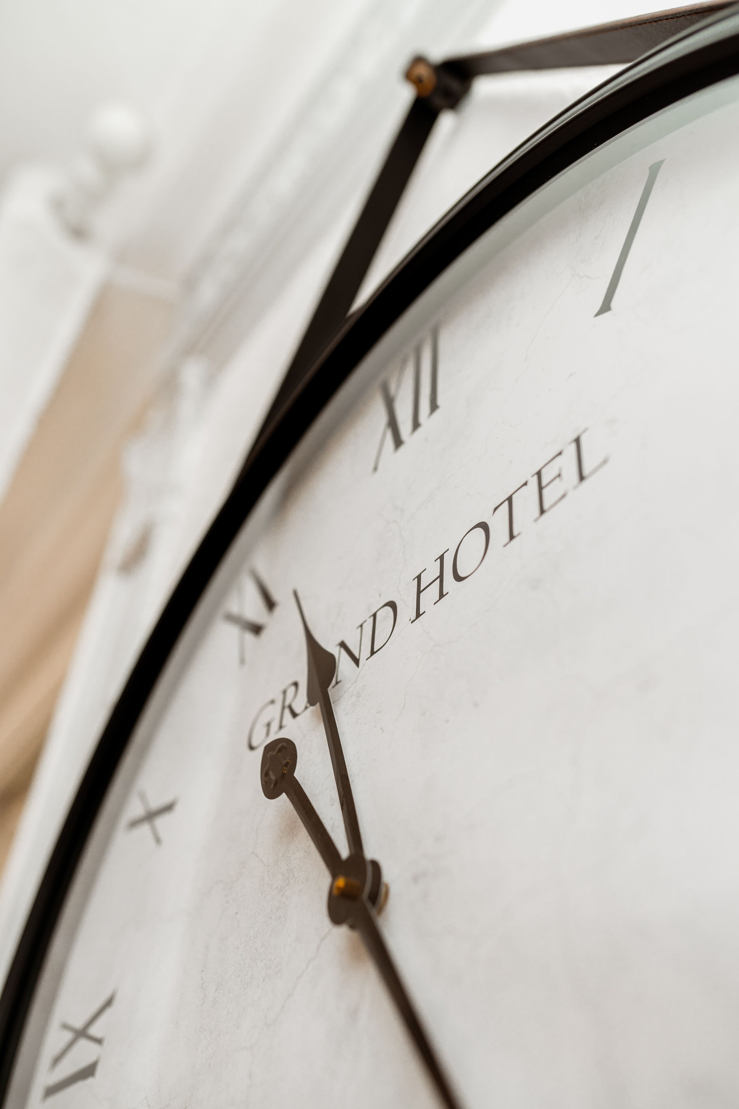 A close-up of a clock with Roman numerals and the words "GRAND HOTEL" on its face.