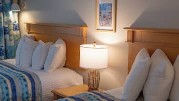 A hotel room with two beds, a bedside table with a lamp, a framed picture on the wall, and a curtain with a fish pattern.