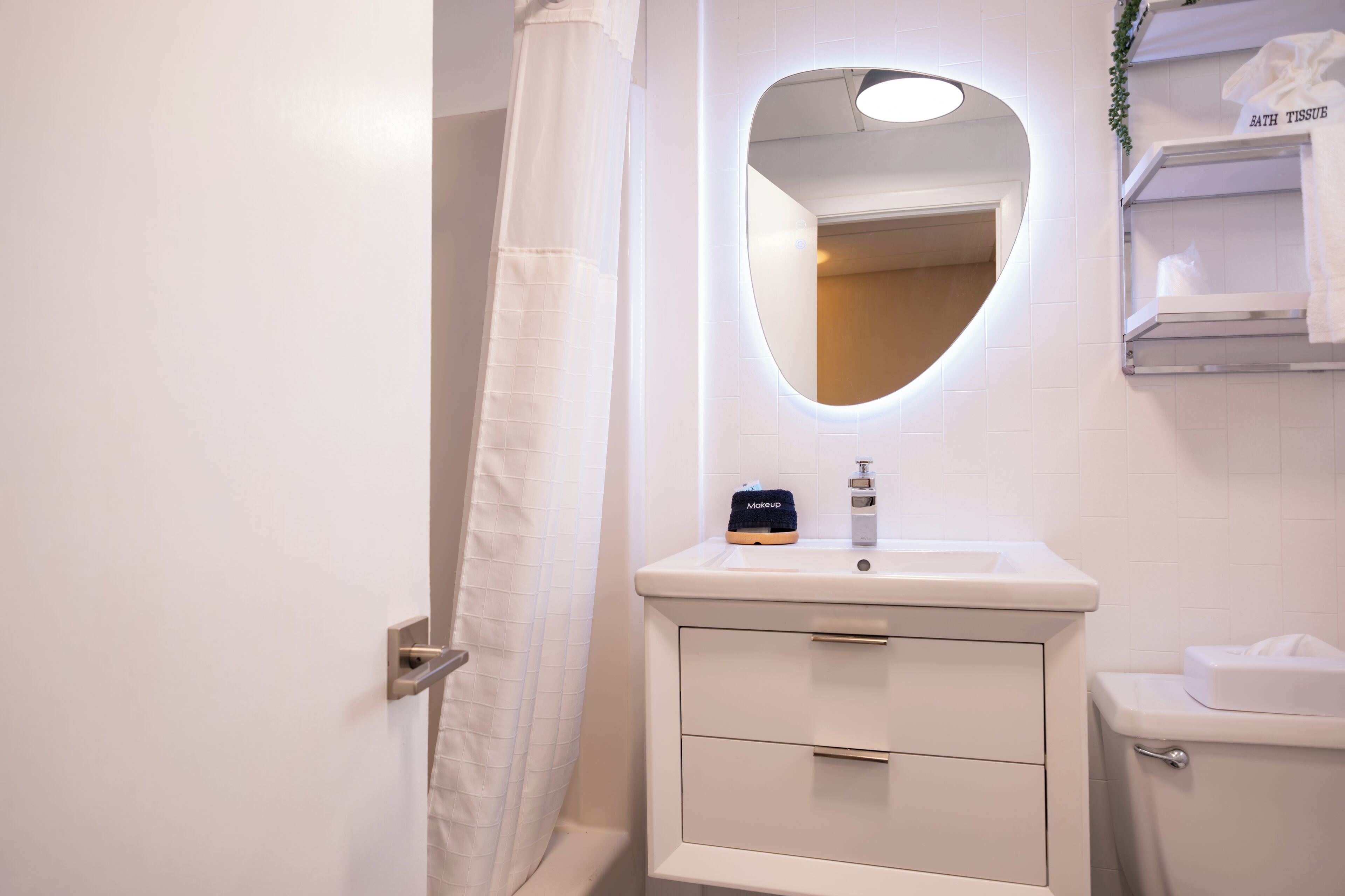 Une salle de bain avec un lavabo blanc, un miroir, des toilettes et un rideau de douche.
