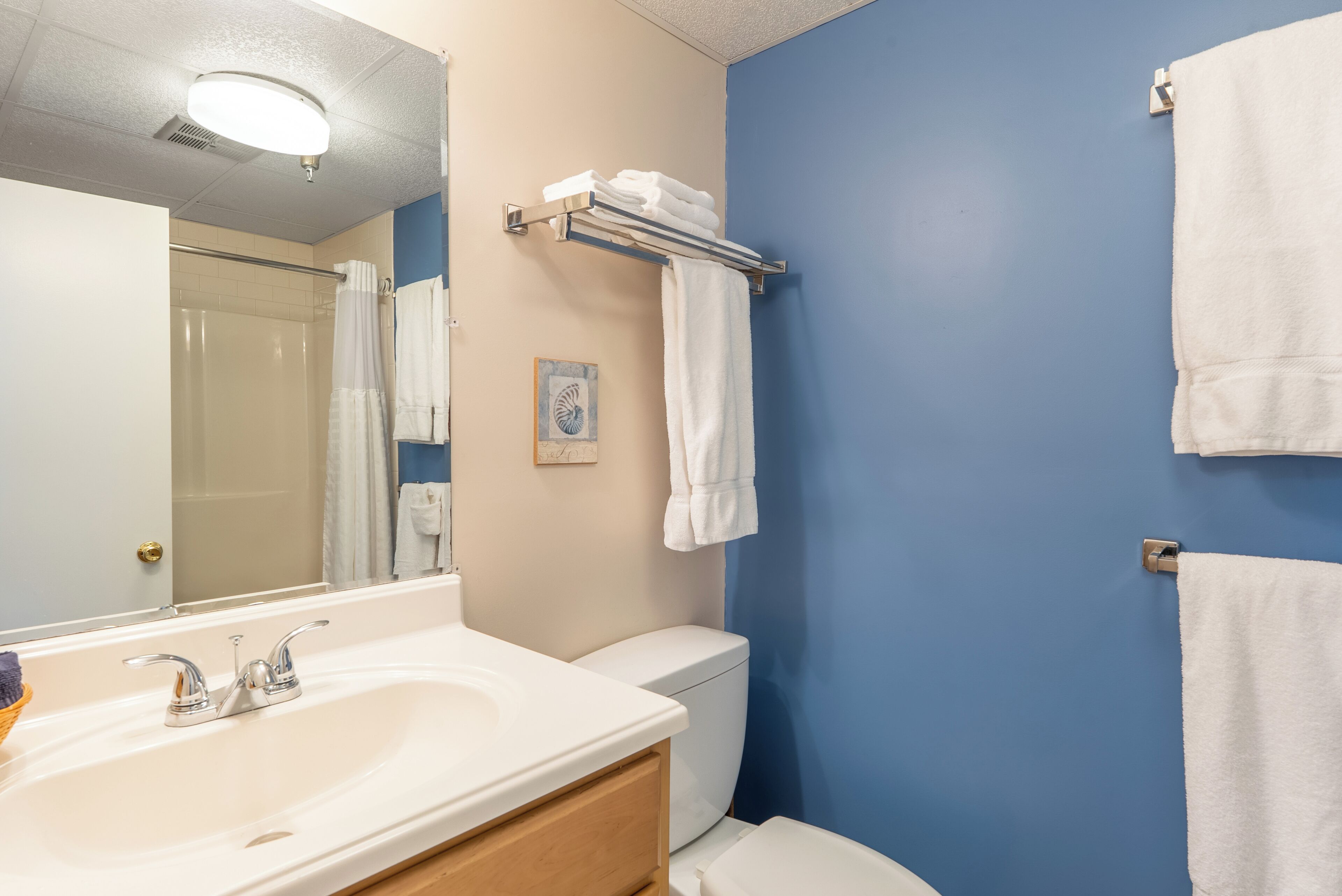 A bathroom with a white sink, a mirror, a toilet, and a towel rack.